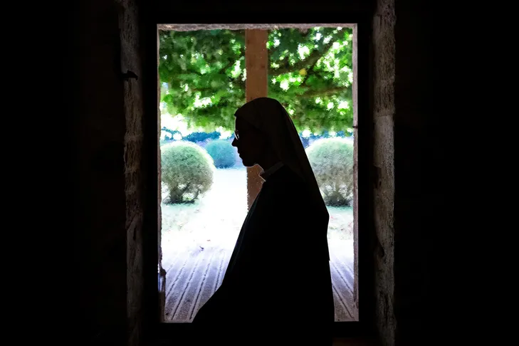 Une religieuse à contre-jour devant une fenêtre