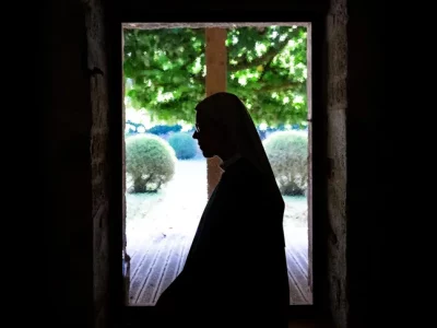 Une religieuse à contre-jour devant une fenêtre