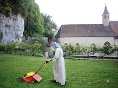 Monastere Sainte Claire, fonde par Sainte Colette, a Poligny, lieu de vie de la communaute des Clarisses de Flavigny.
Soeur, religieuse en train de tondre, tondesue a gazon, tonte de la pelouse, entretien des dependances, jardin  du monastere.
La regle des Clarisses est batie sur l'abandon des biens et la totale pauvrete.